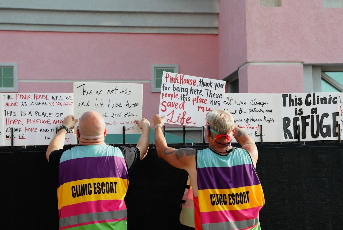 Des «escorts» appartenant à la clinique retirent des panneaux sur les murs d’enceinte de l’établissement.