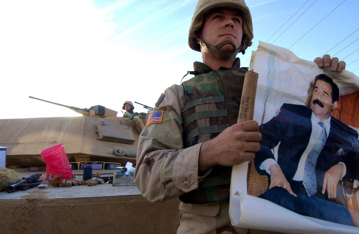 Un soldat américain montrant un poster de l’ancien dictateur irakien Saddam Hussein. (Photo d’archive)