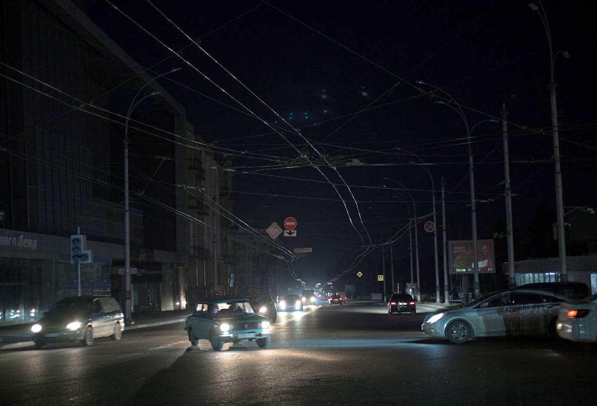 Des voitures roulent dans une rue sombre pendant une panne d'électricité à Kharkiv, en mars 2024.