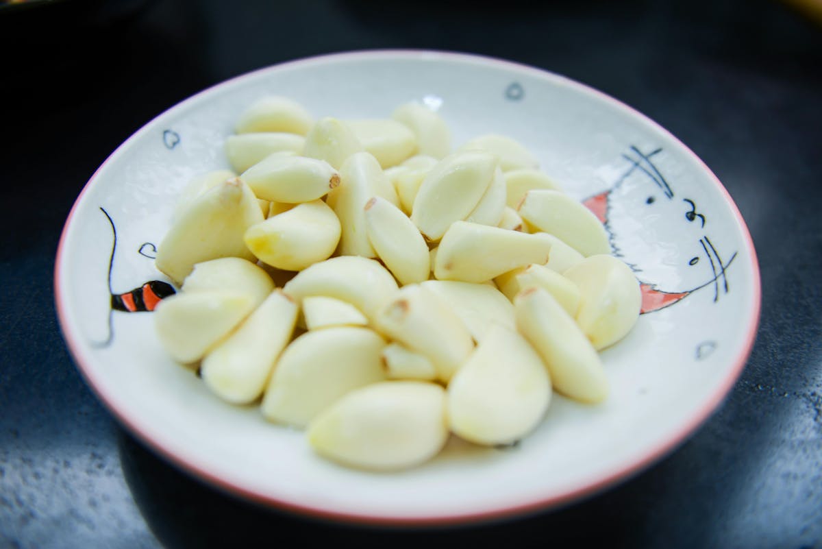 You can press fresh garlic cloves with the flat side of a knife.  Crushing breaks up the cells and releases the flavors.